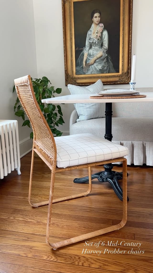 Set of six mid-century Harvey Probber rattan chairs beneath a gilt-framed portrait