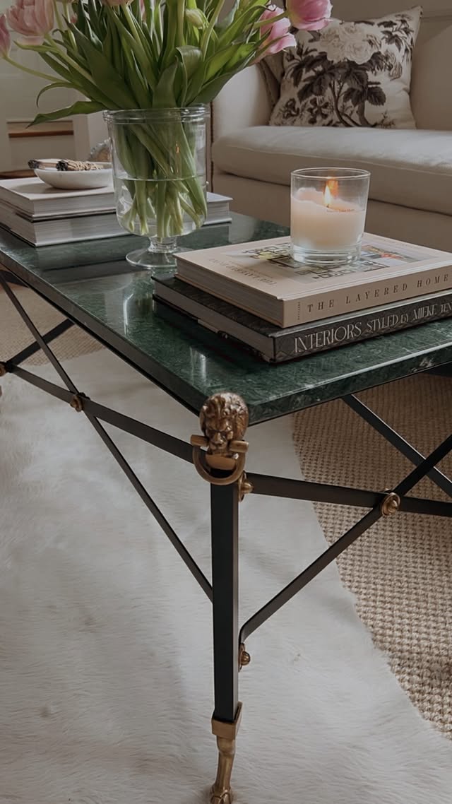 Green marble and iron coffee table with lion's-head brass detail, tulips and a lit candle